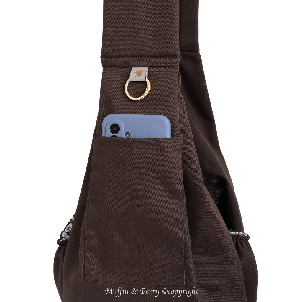 Close-up of BONNIE brown pet sling carrier front pocket with smartphone, gold O-ring and trench fabric texture detail, by Muffin & Berry