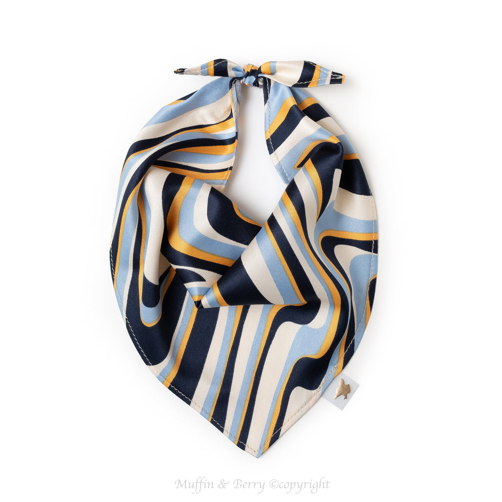 Dog bandana KELLY with navy, light blue, gold and cream abstract waves, tied at the top against a white background, by Muffin & Berry